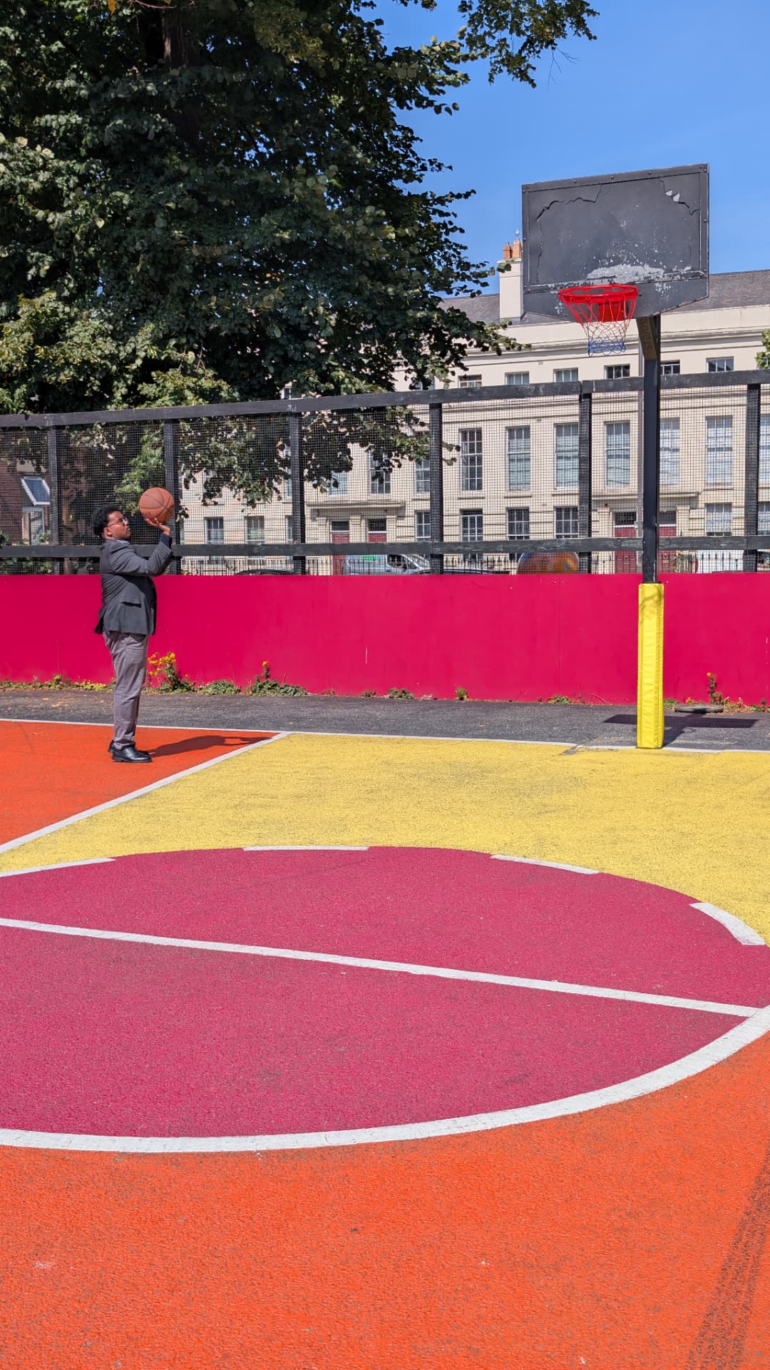 Abdi Ahmed taking a shot on a colourful outdoor basketball court