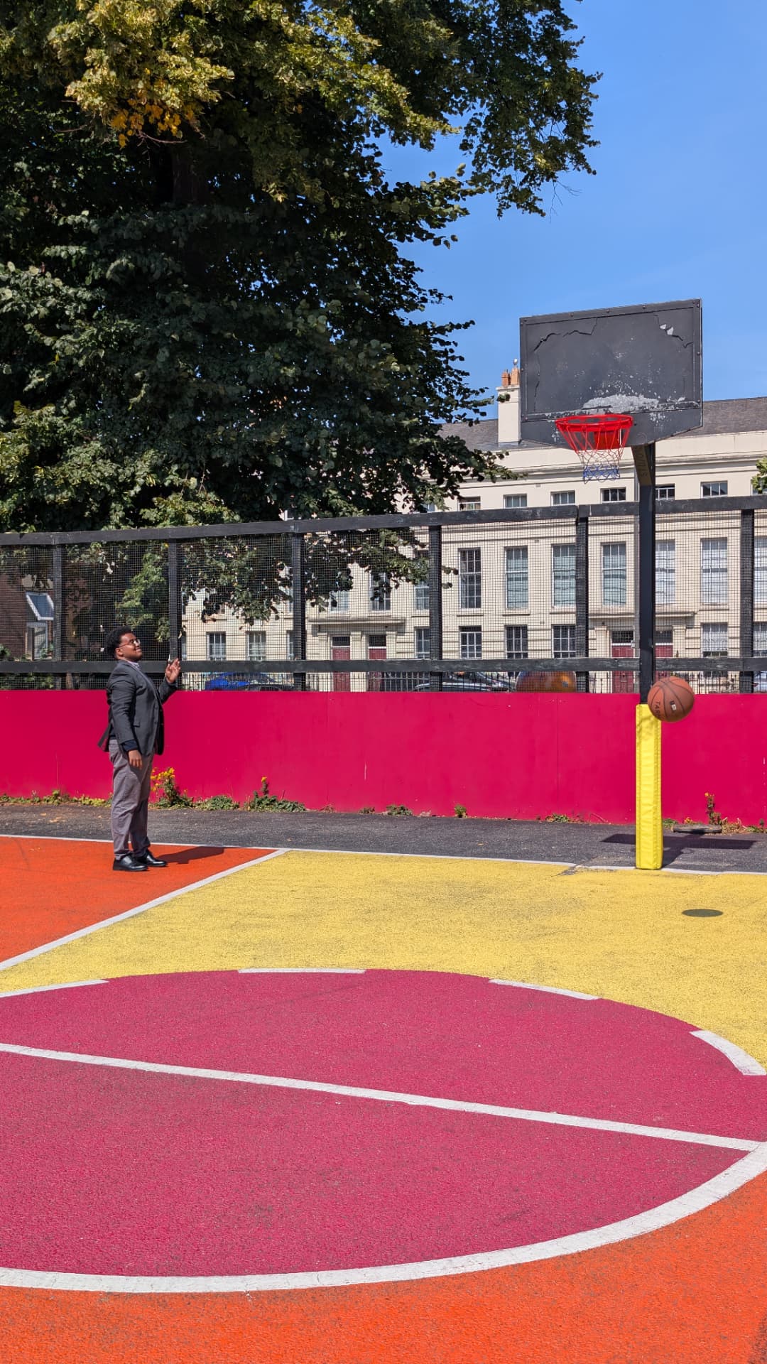 A basketball in mid-air above the court as Abdi Ahmed watches